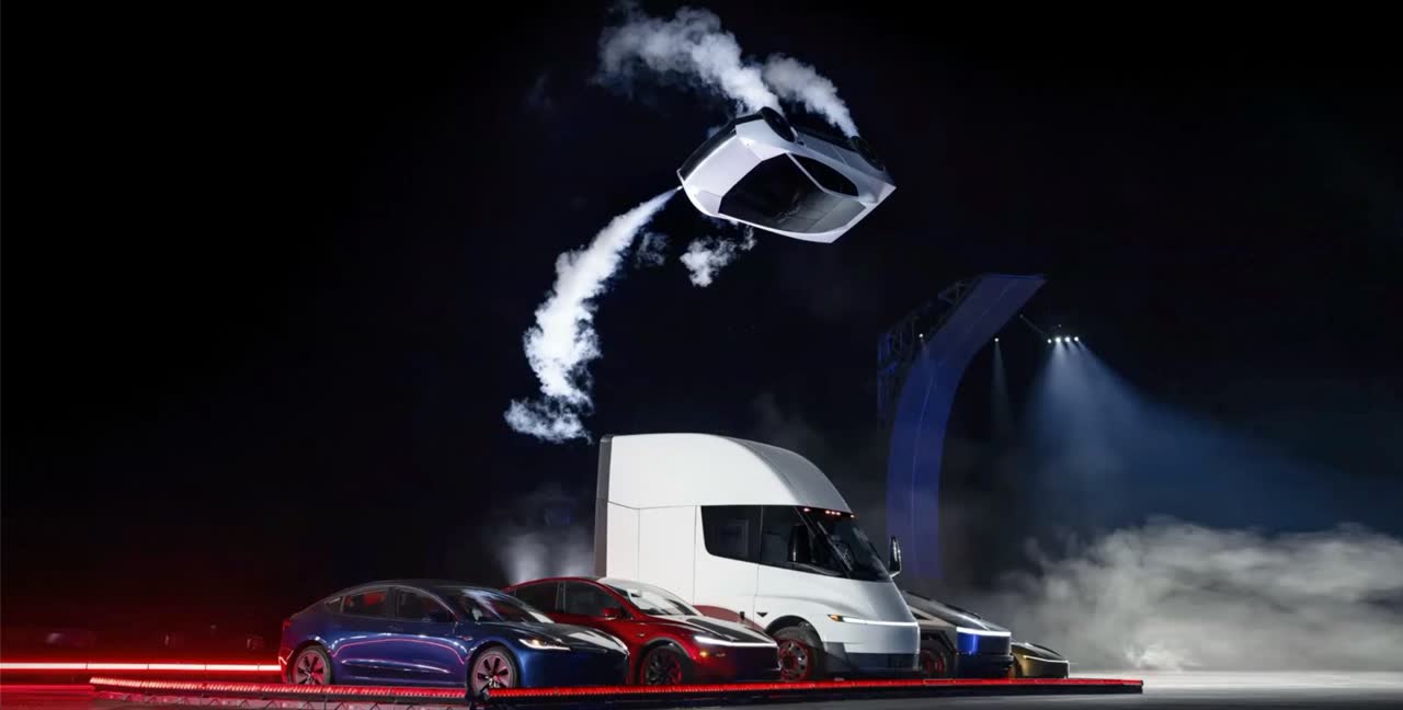 The white Roadster upside down mid-kickflip, trailing thruster vapor, high above a Tesla Semi and a line of Teslas